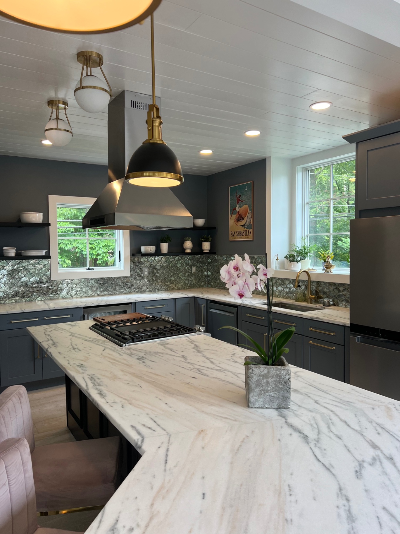 Marble island kitchen with deep slate cabinetry and brass accents