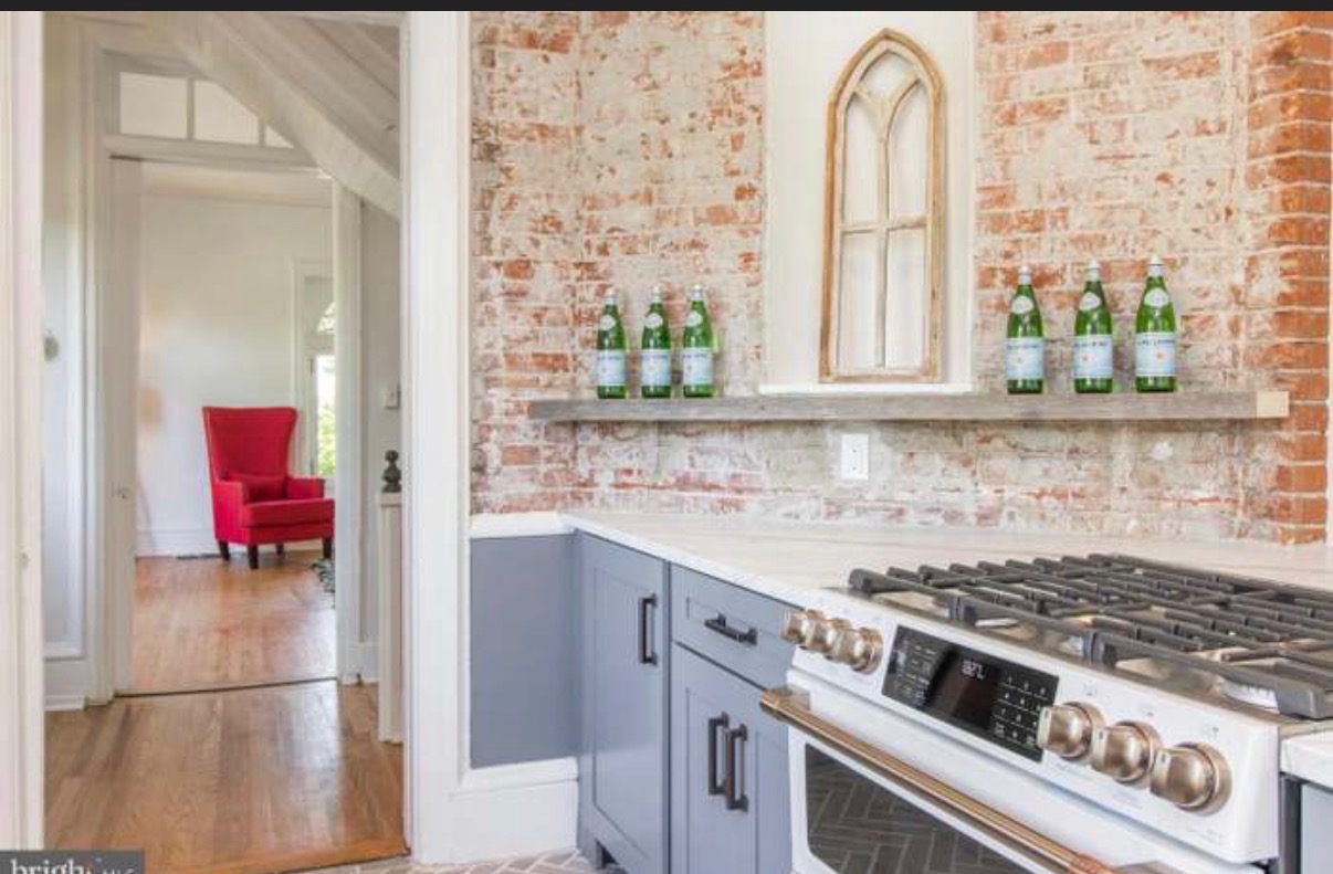 Galley kitchen with exposed brick wall and reclaimed wood shelf